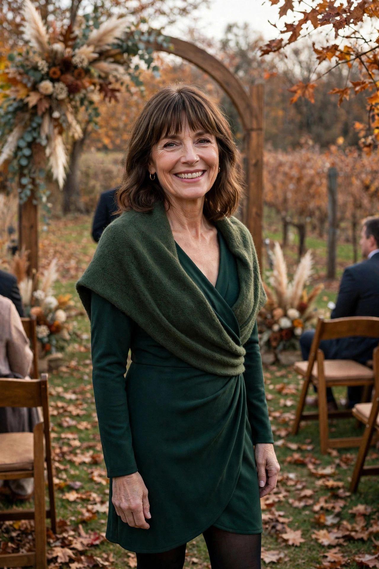 Woman in a deep green wrap dress with a wool shawl and tights at a late autumn wedding ceremony, a layered fall wedding guest dress for cooler weather.