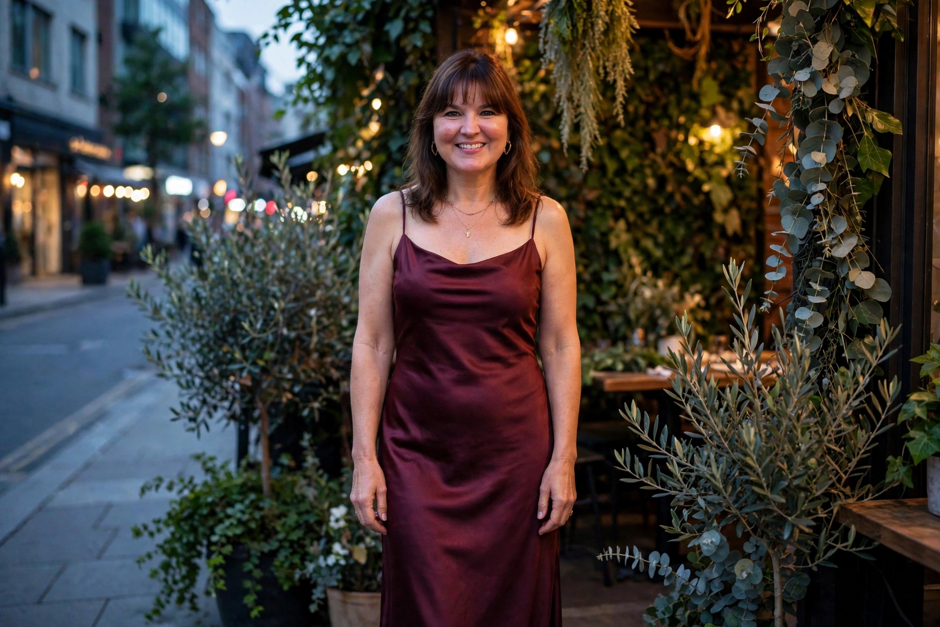 Woman with shoulder-length brown hair and bangs wearing an emerald satin evening gown